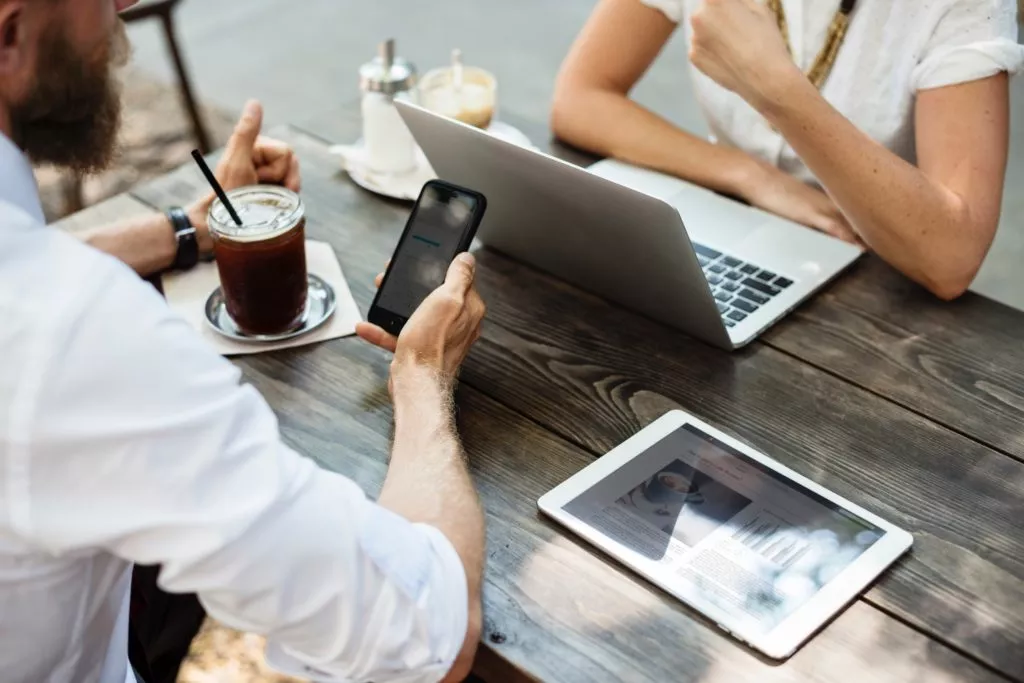 two people sitting at a table with a laptop, tablet and phone discussing dental HR practices